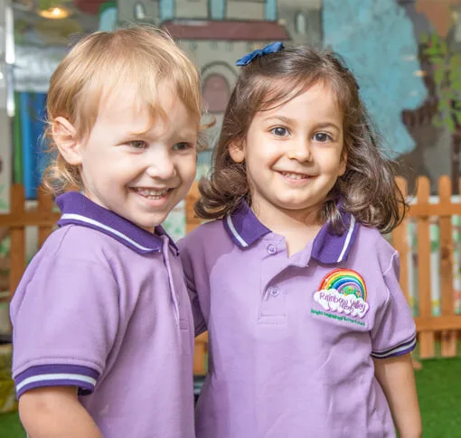 Two children in Rainbow Valley Nursery uniform smiling outdoors