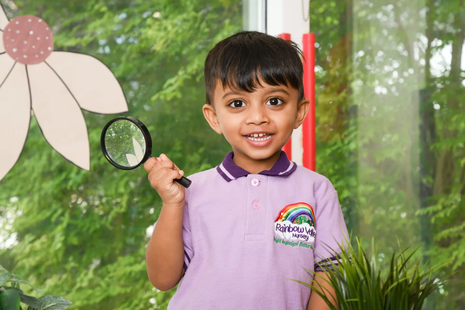 Boy in Rainbow Valley Nursery uniform holding a magnifying glass