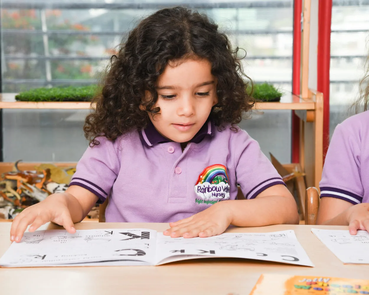 Girl in Rainbow Valley Nursery uniform working in an activity book